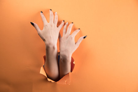 female hand tearing orange paperの写真素材