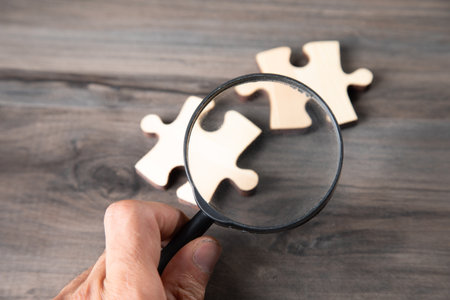 a magnifying glass and puzzle pieces on the tableの写真素材