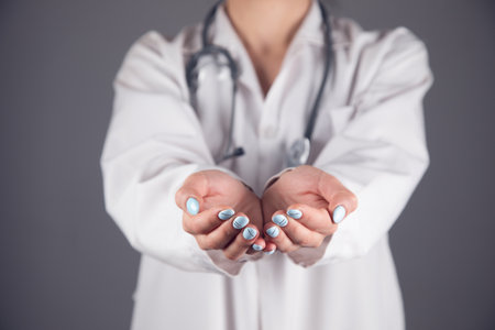doctor holding empty palms on gray backgroundの写真素材