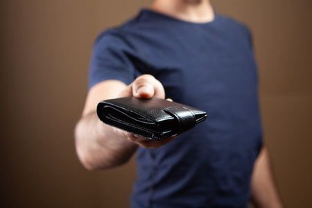man gives wallet on brown backgroundの写真素材