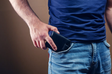 man puts wallet in front pocket on brown backgroundの写真素材