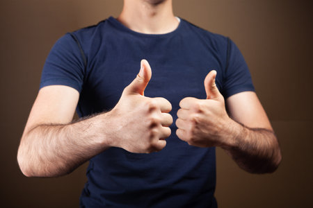 man showing thumbs up on brown backgroundの写真素材