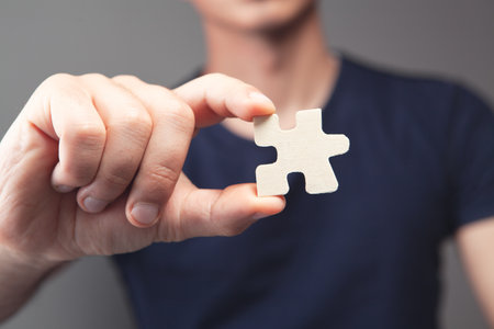 man holding puzzle piece on gray background