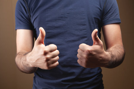 man showing thumbs up on brown backgroundの写真素材