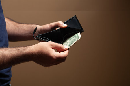 a man pulls out money from a wallet on a brown backgroundの写真素材