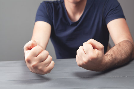 hits the table with his fist on a gray backgroundの写真素材