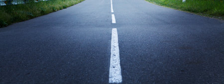 an asphalt road goes through the fields in the eveningの写真素材