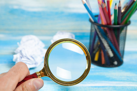 pencils in a stand, a magnifying glass and crumpled papers on the table. concept idea for drawingの写真素材