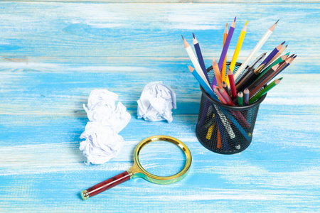 pencils in a stand, a magnifying glass and crumpled papers on the table. concept idea for drawingの写真素材