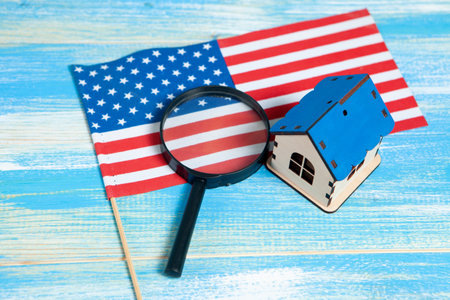 magnifier, American flag and house. home search concept. home inspection on a blue tableの写真素材