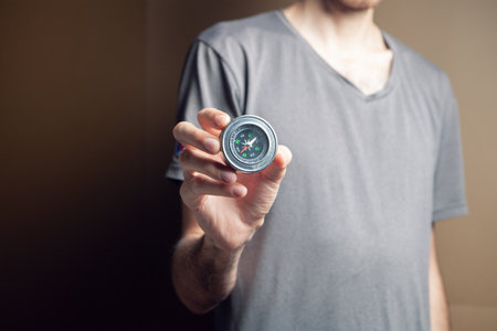 man holding compass on brown backgroundの写真素材