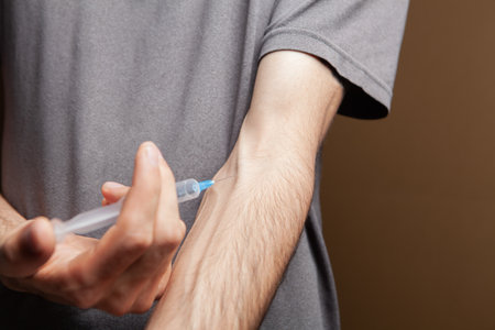 drug addict gives himself an injection on brown backgroundの写真素材