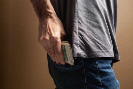 man puts money in his back pocket on brown background