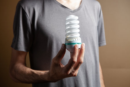 man holding ecological light bulb on brown backgroundの写真素材