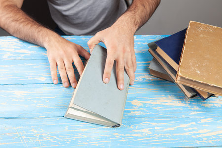 a man sits in front of books and opens a bookの写真素材