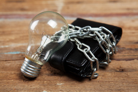 wallet in chains and a light bulb on the tableの写真素材