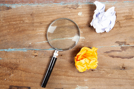 magnifier and crumpled papers on a wooden table. concept search for an ideaの写真素材
