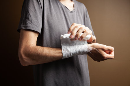 man tied his hand with a bandage on a brown backgroundの写真素材