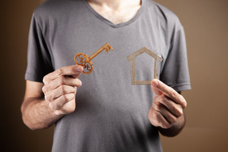 young man holding keys and mock house on brown backgroundの写真素材