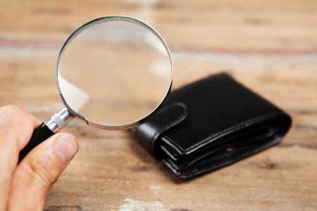 wallet and magnifier on wooden backgroundの写真素材