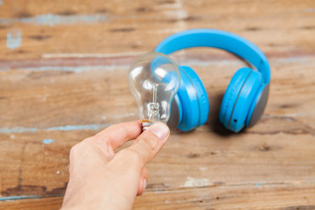 light bulb and headphones on a wooden tableの写真素材