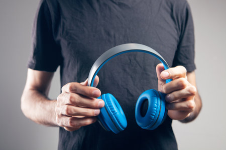 man holding big headphones in his handsの写真素材
