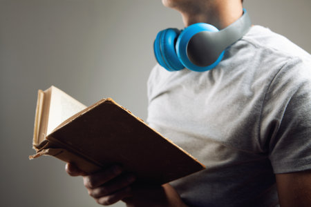 a man stands with a book and with headphones. audiobookの写真素材