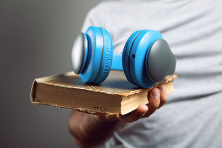 a man stands with a book and with headphones. audiobookの写真素材