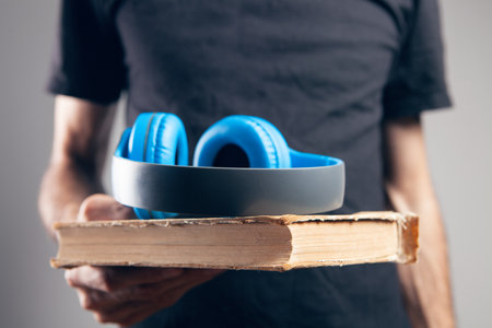 a man stands with a book and with headphones. audiobookの写真素材