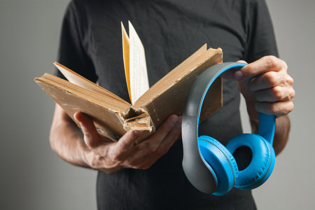 a man stands with a book and with headphones. audiobookの写真素材