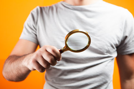 man holding a magnifying glass on orange backgroundの写真素材