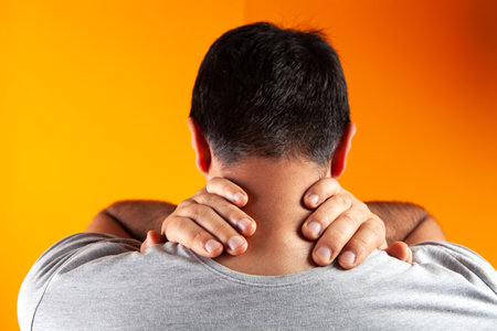 Man has neck pain on orange background