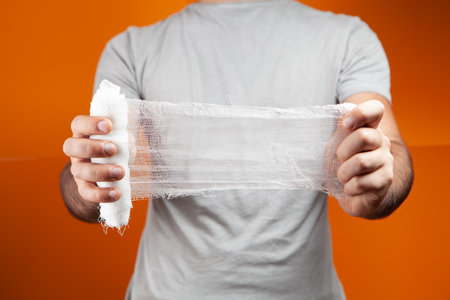 a man holding a bandage on a orange backgroundの写真素材