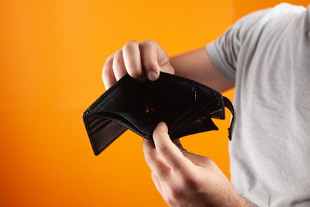 man showing empty wallet on orange background