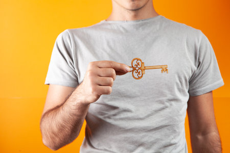 man holding house keys on orange backgroundの写真素材