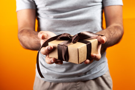 man holding a gift box in his hand. on an orange background