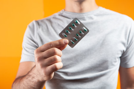 guy holding pills in his hands on an orange backgroundの写真素材