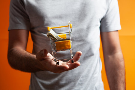 holding a basket with money on an orange background
