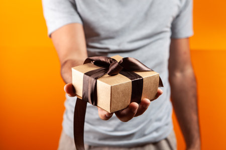 man holding a gift box in his hand. on an orange background