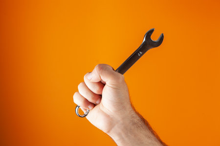 hand holds a wrench on an orange backgroundの写真素材
