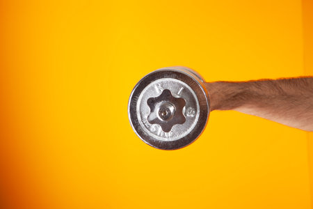 man holding dumbbell on orange backgroundの写真素材