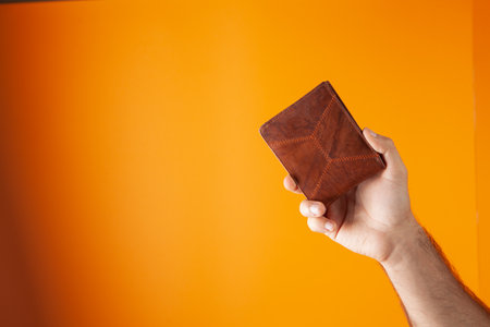 hand holds wallet on orange background