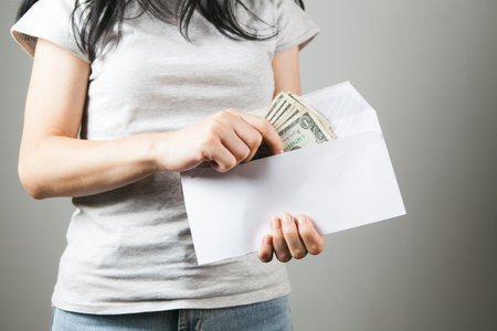 woman pulls money out of an envelopeの写真素材