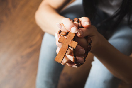 woman holding a cross and praying on the floorの写真素材