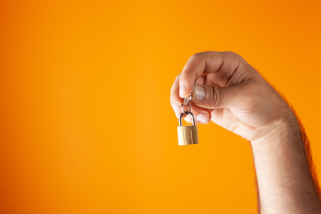 hand holds padlock on orange backgroundの写真素材