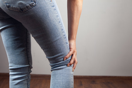 woman has knee pain on gray background