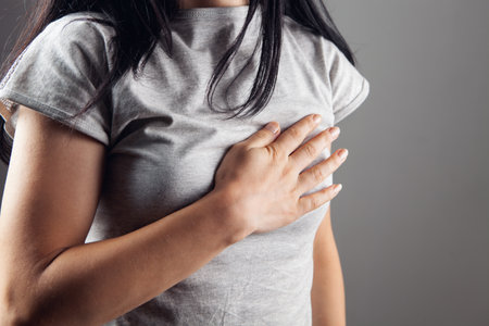 woman has chest pain on gray backgroundの写真素材
