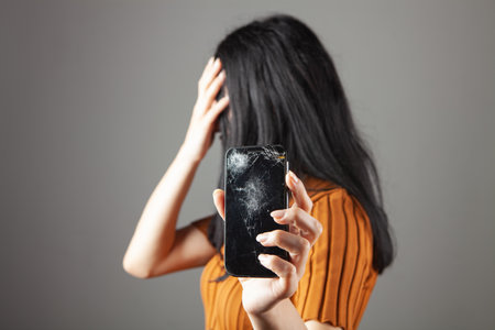 woman showing broken phone screen on gray background