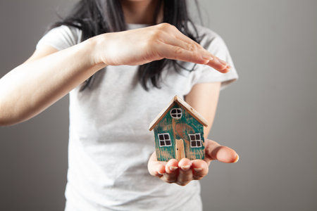 young woman holding a house in her handsの写真素材