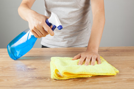 woman with a rag and detergent washes the table